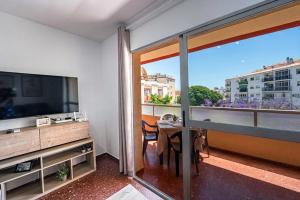 a room with a television and a balcony with a table at Bright & Spacious Apartment in Nerja Centre in Nerja