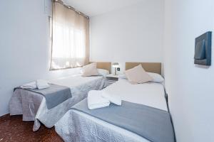 two beds in a room with a tv and a window at Bright & Spacious Apartment in Nerja Centre in Nerja