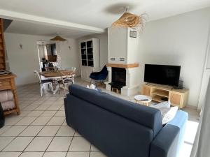 a living room with a blue couch and a tv at La Blériotine in Sangatte