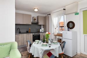 a kitchen with a table and chairs and a white refrigerator at Kuća Lucija in Supetar
