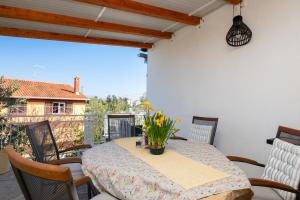 a table and chairs on a balcony with a table and flowers at Kuća Lucija in Supetar