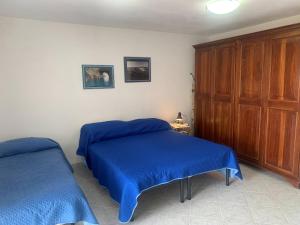 a bedroom with two beds with blue sheets at Casa Il Timone Indipendente in Ponza