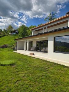 a house with large windows and a green lawn at Moon Lake Bicaz - Aurora Garden in Buhalniţa