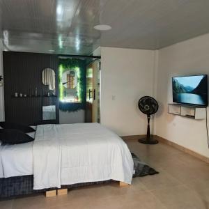 a bedroom with a white bed and a flat screen tv at Suite campestre a 5 minutos del parque con aire acondicionado in Acacías
