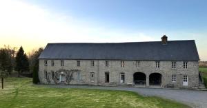 a large stone building with a black roof at Escapade au cœur du Haras in Le Mesnil-Rouxelin