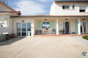 a white house with a table and chairs at Maison venitia t5 in Aussonne