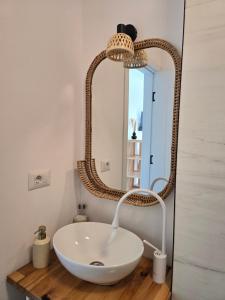 a bathroom with a white sink and a rattan mirror at Moon Lake Bicaz - Aurora Garden in Buhalniţa +31 photos