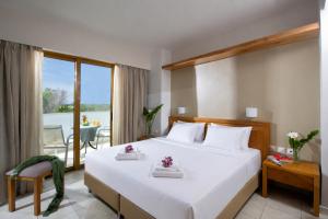 a bedroom with a large white bed and a balcony at Mary Hotel & Mary Royal Suites in Platanes