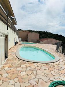 a large swimming pool on a patio with a stone floor at Costa Silvia Villaggio Frisaia Vue imprenable sur la mer avec piscine in Trinità d'Agultu e Vignola
