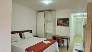 a bedroom with a bed and a desk and a mirror at Lagamar Hotel Varginha in Varginha +37 photos