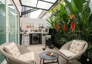 a patio with two chairs and a table with wine glasses at SvoyLuX Primo 3BR Gated House Near Pier and Muay Thai Street in Phuket