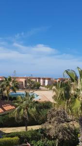 a view of a resort with palm trees and a pool at casabianca north coast villa code 112 in Dawwār Muḩammad Abū Shanab