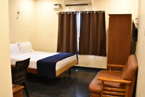 a small room with a bed and a chair at Vybhav Residency in Anantapur