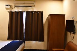 a bedroom with a bed and a window with a curtain at Vybhav Residency in Anantapur