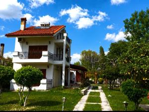 a white house with a red roof on a green yard at Coral Bungalow in Rákhai