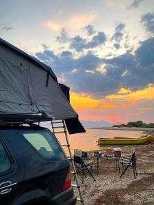 a car parked on a beach with a tent and chairs at lodi campers rental in Theth