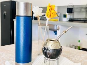 a blue thermos and a vase with flowers on a table at Los Olivos Apart in Cafayate