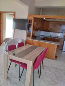 a kitchen with a wooden table and pink chairs at JIMMYS HOME in Skala Prinou