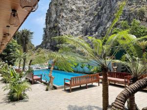 a pool with benches and palm trees in front of a mountain at Tam Coc Mountain Ecolodge in Ninh Binh +21 photos