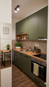 a kitchen with green cabinets and a sink and a table at Apartman Mima in Inđija