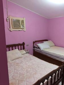 two beds in a room with purple walls at Diamond Beach In Marina, Egyptw in Dawwār Abū Maḩrūs