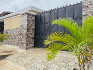 a building with a black gate and a palm tree at Abi's Place Benin in Benin City
