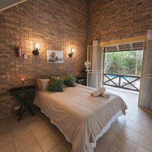 a bedroom with a large bed in a brick wall at Dumela Afrika in Marloth Park
