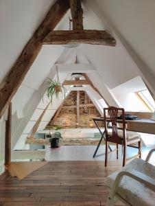 a room with a table and a chair in a attic at Le refuge, 4 personnes in Envermeu