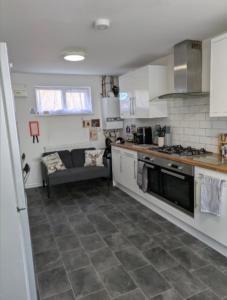 a kitchen with a stove and a couch in it at Corby Double & En-suite Rooms NN17 2LZ area Ideal Contractors Short & Long stays Opposite Lodge Park Leisure Center in Corby