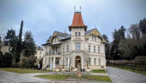 a large white house with a tower on top at Garsonka - Luhačovice in Luhačovice