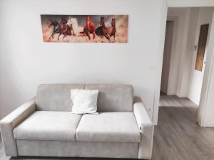 a white couch in a living room with a painting on the wall at La Casina di Orsolina - Check-in Flessibile in Livorno