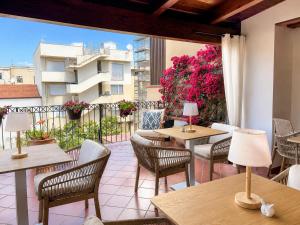 a patio with tables and chairs and a balcony at B&B La Bouganville in Alghero