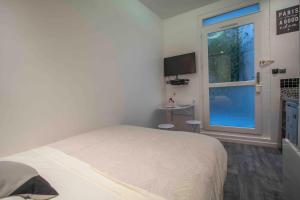 a white bedroom with a bed and a window at Notre Dame Paradis Latin in Paris