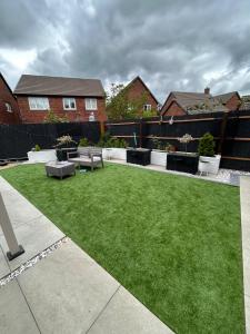 a small backyard with a green yard with benches at Self-Contained Studio with Ensuite & Private Access in Hardwicke