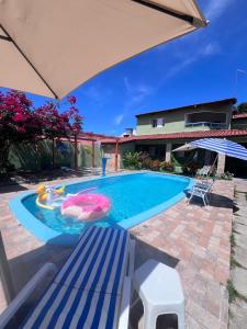 a swimming pool with a table and a bench at Pitimbu Beach House Rosi in Pitimbu