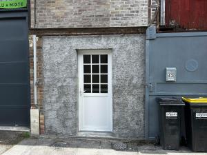a white door on a brick building with two trash cans at Le Petit Gaillard in Les Andelys