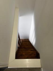 a staircase in a white wall with a wooden floor at Le Petit Gaillard in Les Andelys