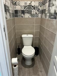 a bathroom with a toilet in a tiled wall at Le Petit Gaillard in Les Andelys