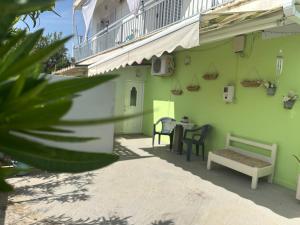 a green building with a bench and a table at Lidas Sunny Guest House Argolis in Nafplio