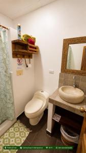 a bathroom with a toilet and a sink and a mirror at Casita Madame - Frente al Mar con Desayuno Gourmet in Puerto López