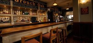 a bar with two chairs and a wooden counter at The Crouch Oak in Addlestone