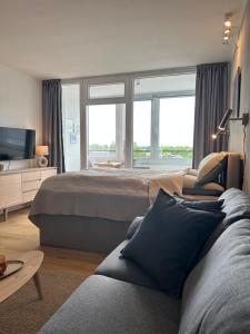 a bedroom with a bed and a couch and windows at Apartment Nordly in Wendtorf