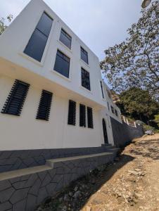 a white house with black windows and a wall at Hotel de la Montaña in Huautla de Jiménez