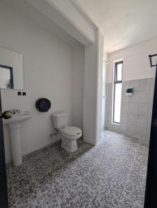 a white bathroom with a toilet and a sink at Hotel de la Montaña in Huautla de Jiménez