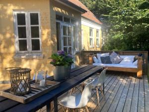 a patio with a wooden table and chairs and a bed at La Petite Ecole in Bindslev