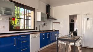 a kitchen with blue cabinets and a table with chairs at Casa El Jazmín in Alfacar