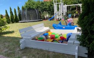 a sandbox with a pile of toys in a park at Bursztynowe Domki in Sarbinowo