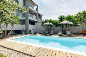 a swimming pool with chairs and umbrellas next to a building at Apartmani Pocco Locco in Biograd na Moru