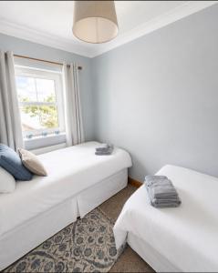 two beds in a room with a window at 11 Netherby Street in Longtown