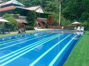 a blue swimming pool with a house in the background at Grand Selva Lodge & Tours in Tena